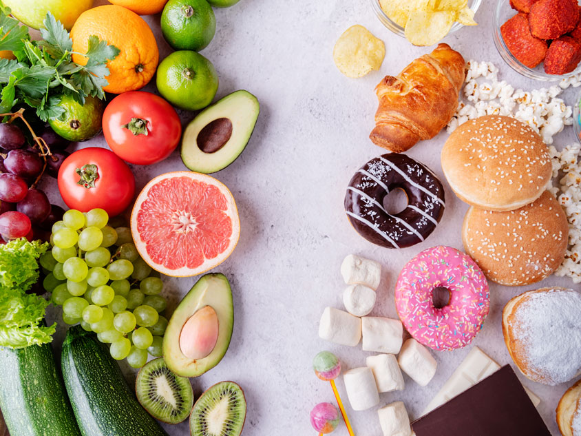 Fruits and vegetables next to donuts and other sweets