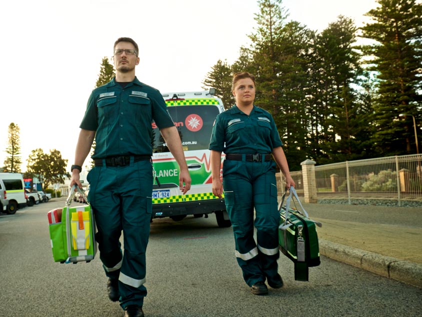 Two paramedics walking in front of an ambulance